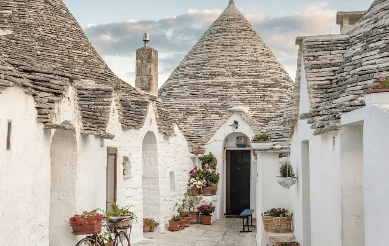 Traditioneller italienischer Trullo mit charakteristischer konischer Steindecke und weißer Fassade in der Landschaft Apuliens