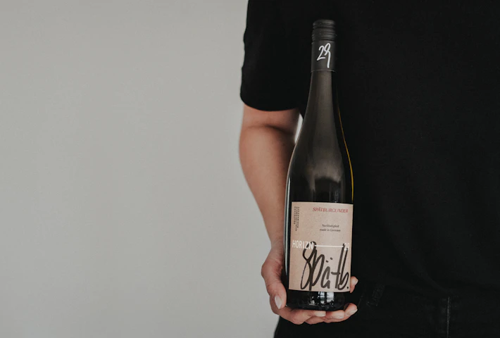 Person präsentiert Flasche der Weinlinie Horizn29